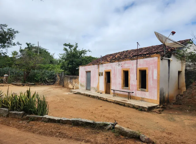 Casa de uma comunidade rural da Caatinga, com terreiro de chão batido e vegetação ao redor